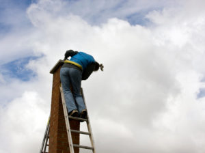 chimney sweep on ladder at the top of chimney